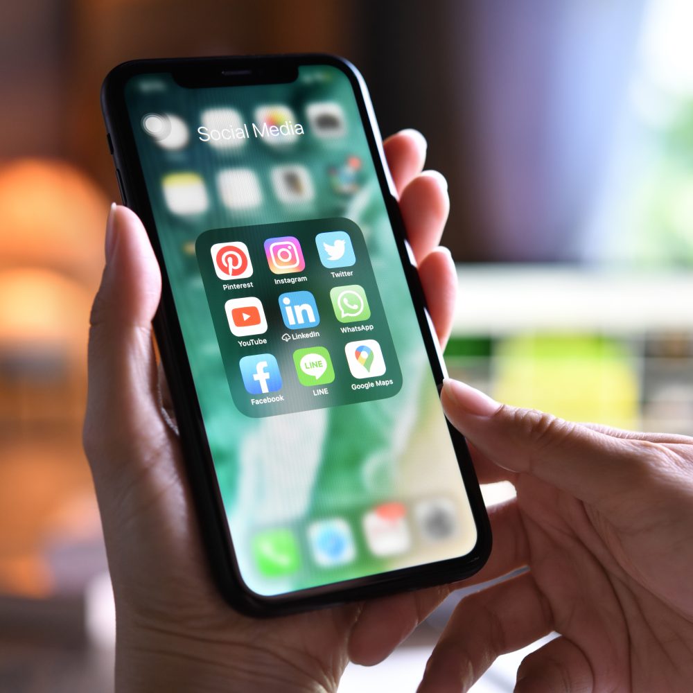 Un smartphone tenu à deux mains, avec ses applications de réseaux sociaux